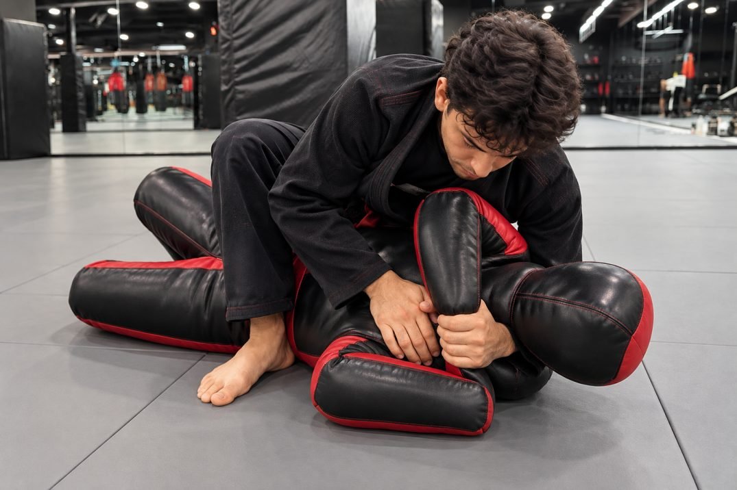 BJJ practitioner practicing Kimura grip positioning with a grappling dummy